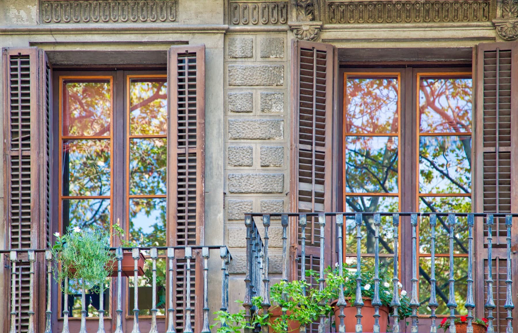 Balcones de hierro forjado y persianas de madera en una finca de época de Barcelona