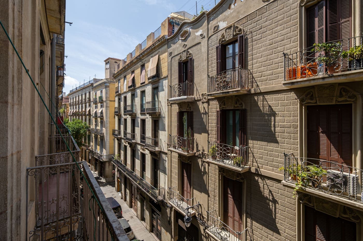 Calle estrecha con balcones de forja, típica de los barrios antiguos de Barcelona como Gràcia